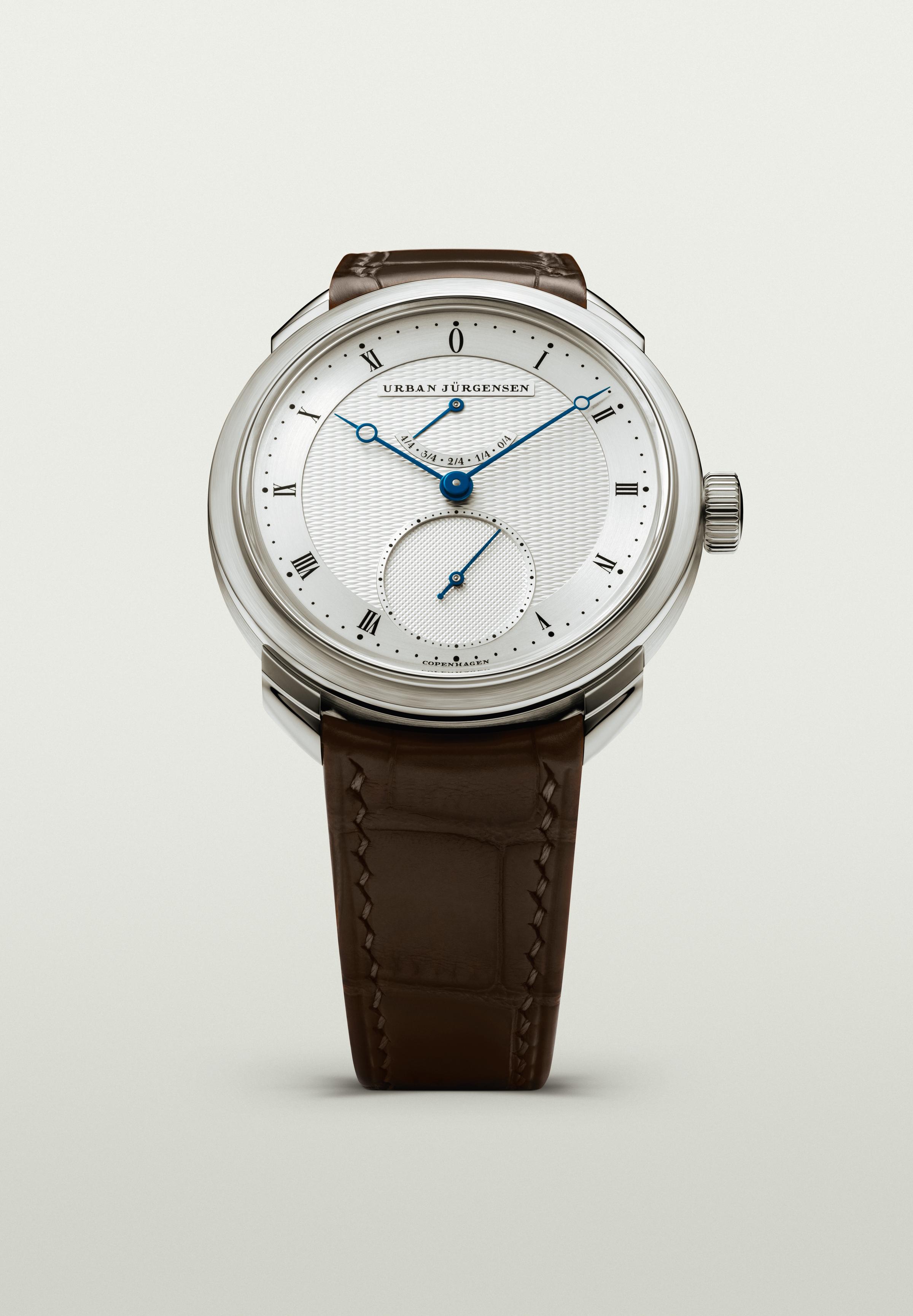 Platinum Urban Jürgensen watch with silver guilloché dial, blued hands, power reserve indicator, and brown leather strap.