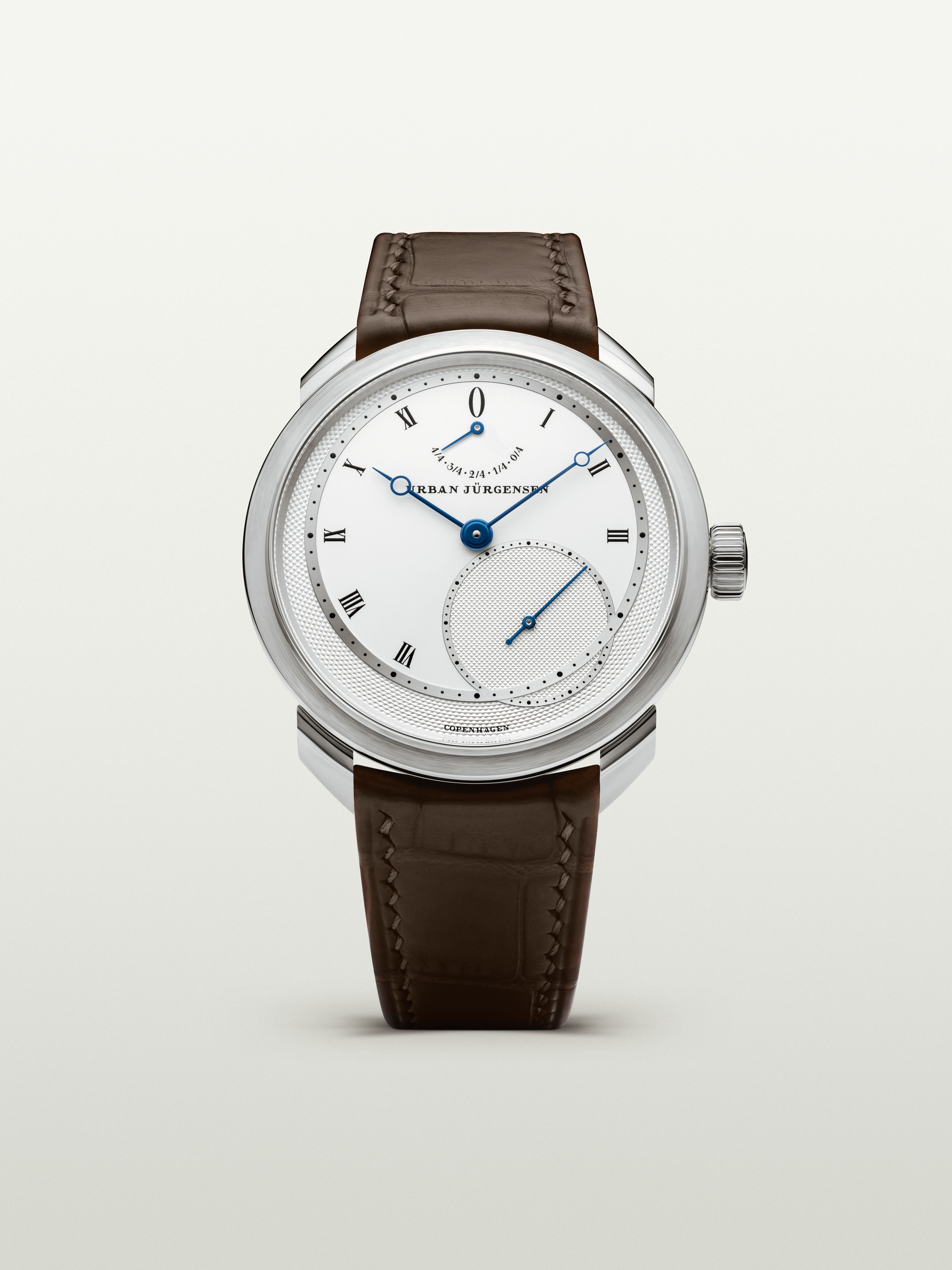 Platinum Urban Jürgensen wristwatch with silver dial, blued hands, Roman numerals, power reserve indicator, and brown leather strap.