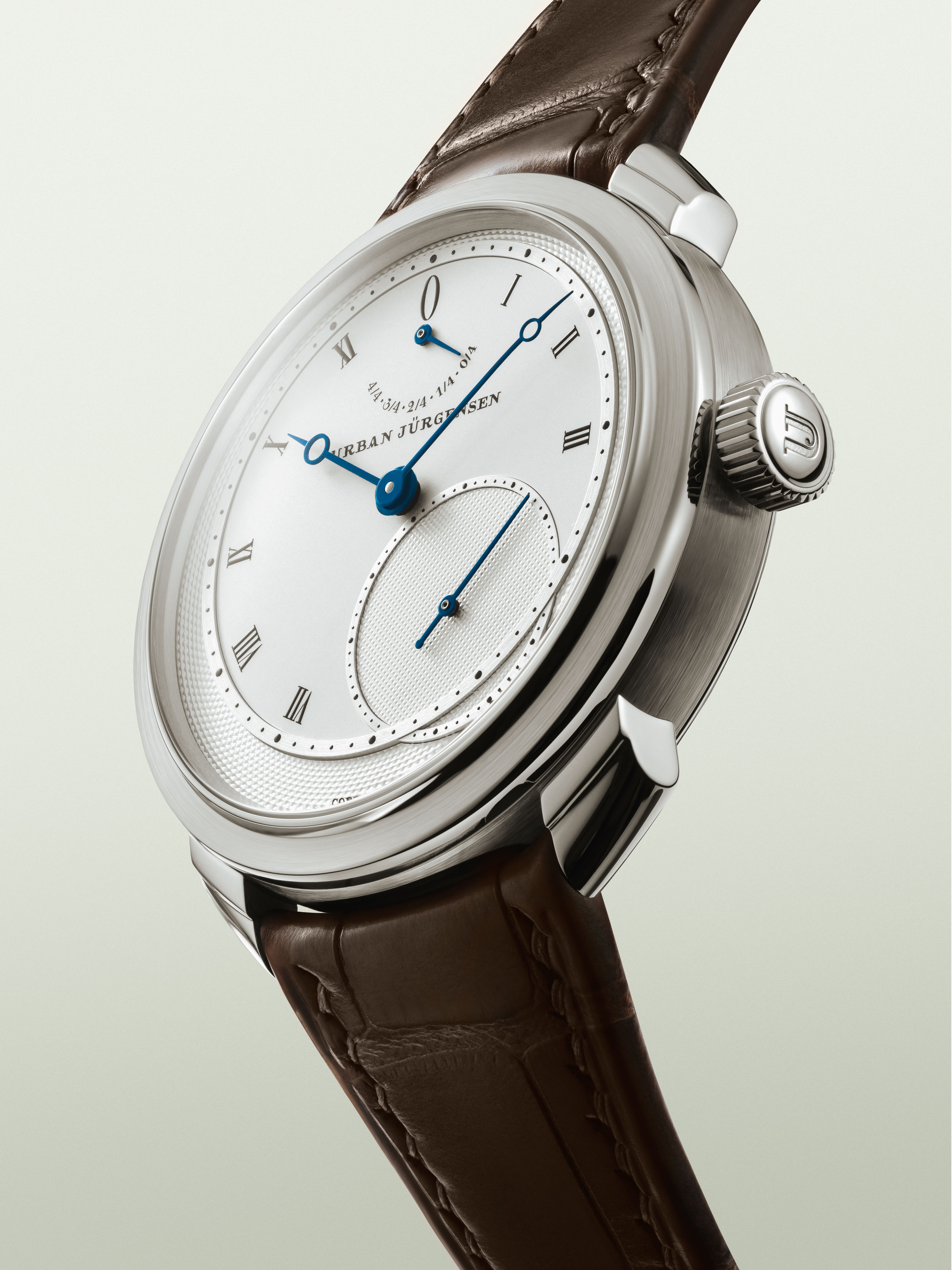 Platinum Urban Jürgensen wristwatch with silver dial, blued hands, Roman numerals, power reserve indicator, and brown leather strap.