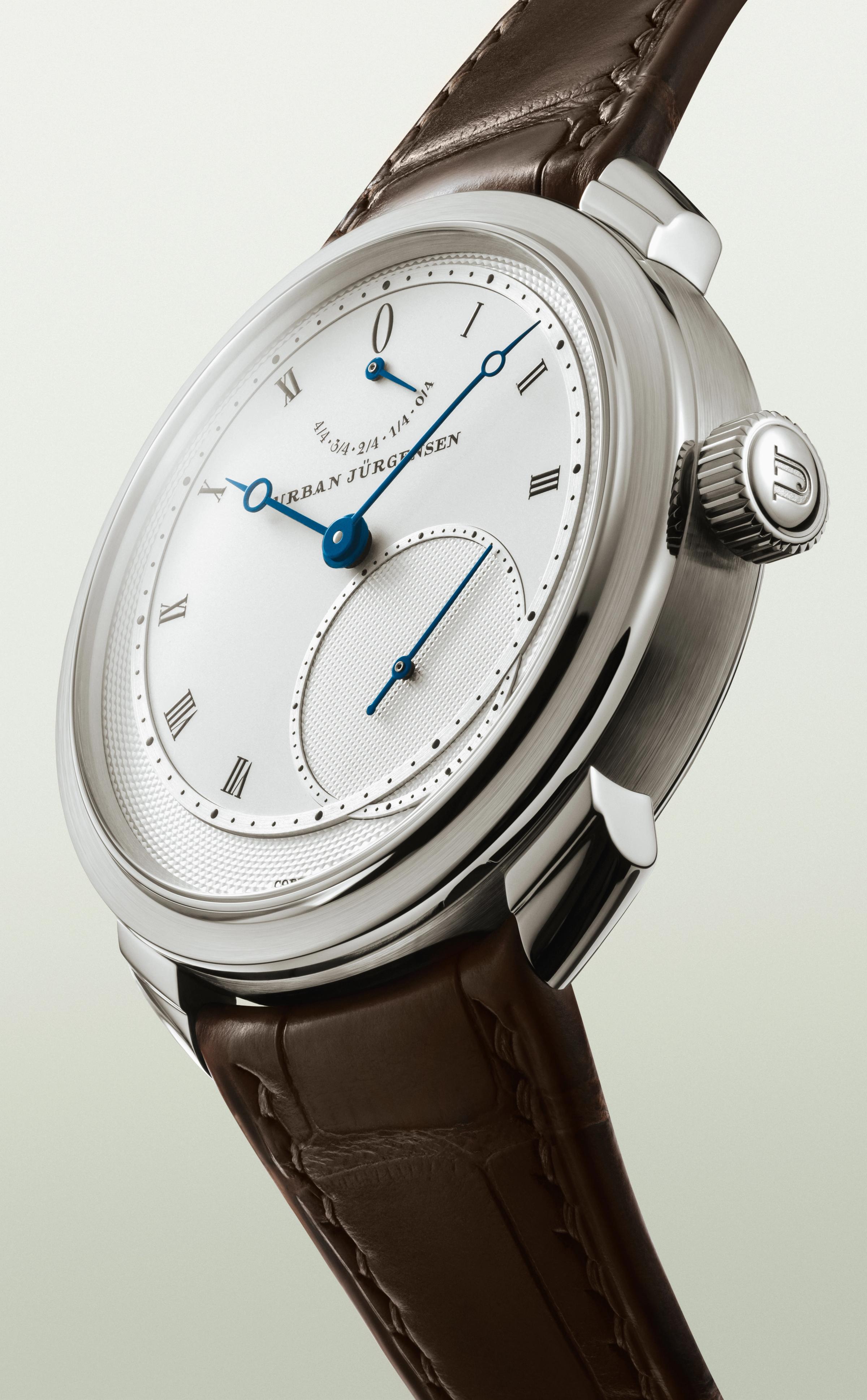 Platinum Urban Jürgensen wristwatch with silver dial, blued hands, Roman numerals, power reserve indicator, and brown leather strap.