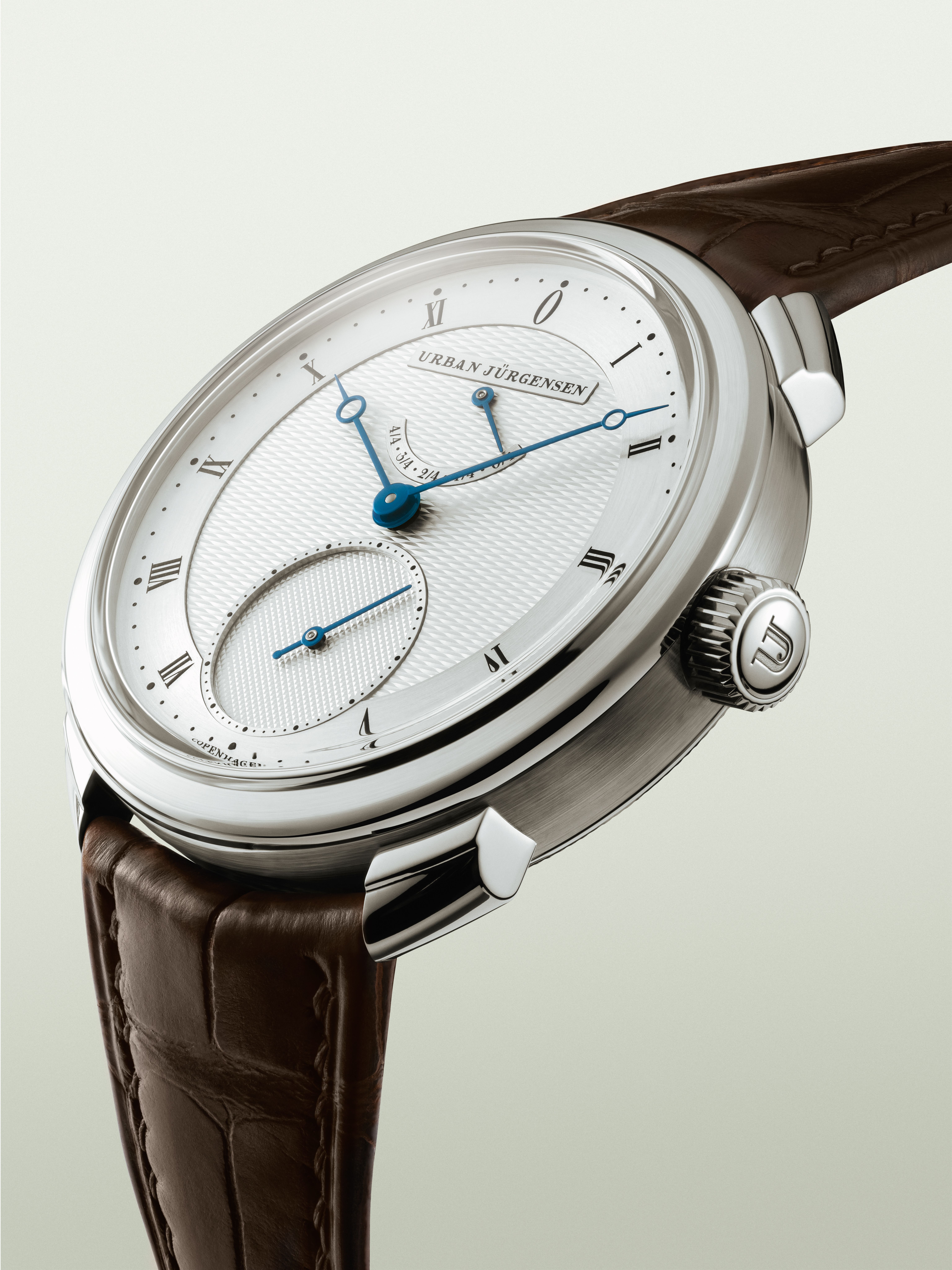 Urban Jürgensen wristwatch with guilloché dial, blue hands, Roman numerals, small seconds subdial, and power reserve indicator.