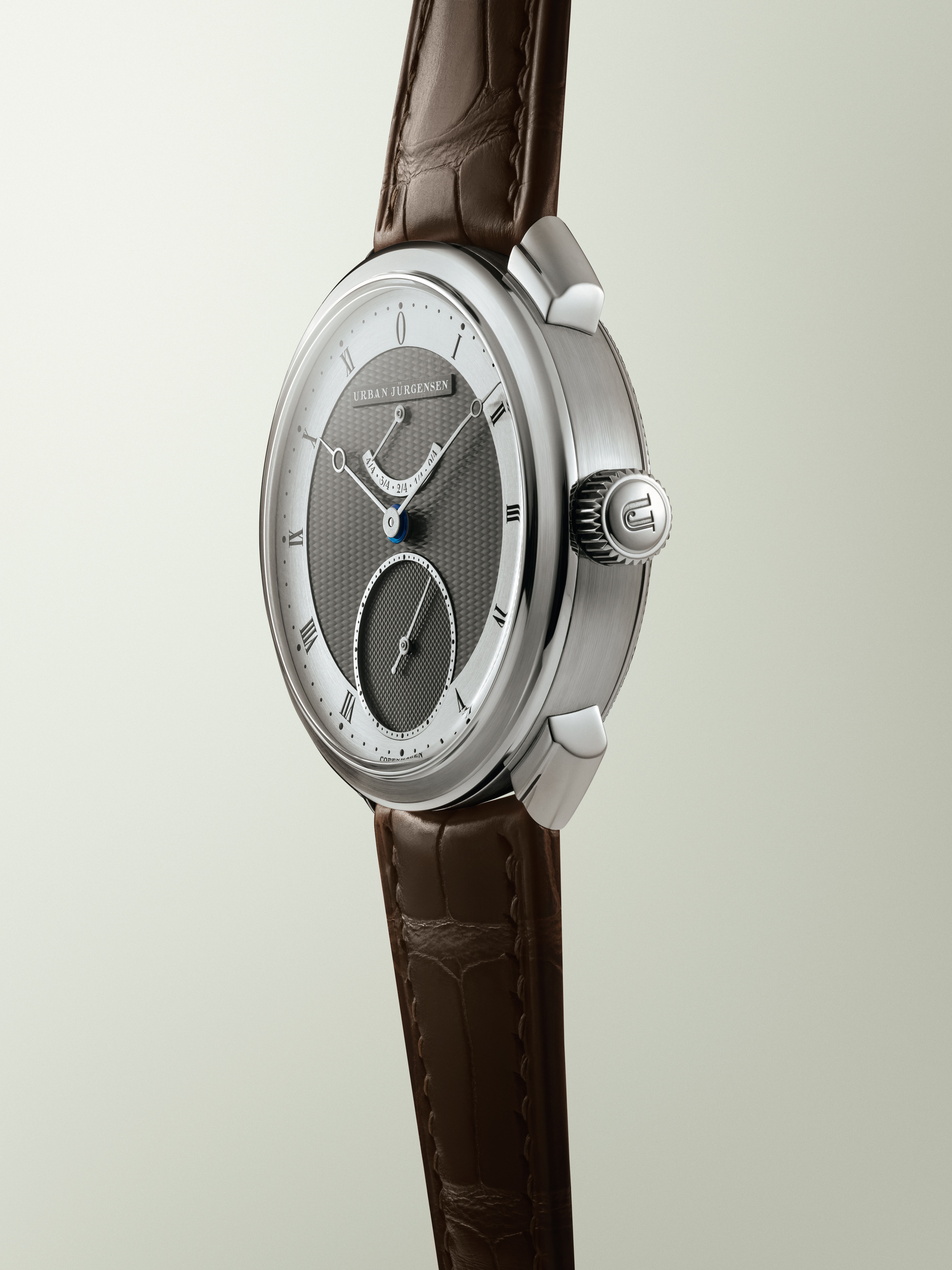 Urban Jürgensen wristwatch with a two-tone guilloché dial, Roman numerals, blued hands, and a brown leather strap.