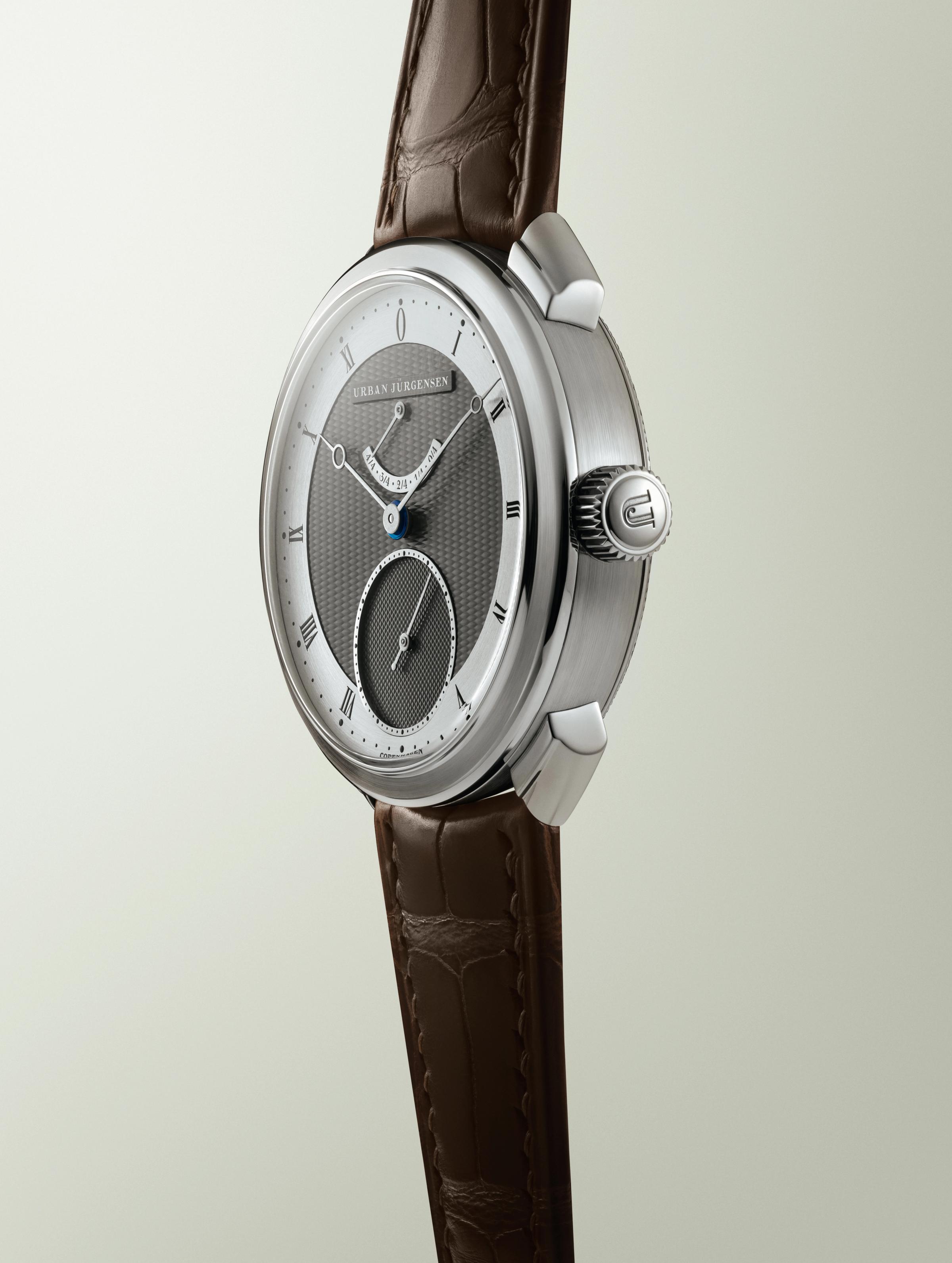Urban Jürgensen wristwatch with a two-tone guilloché dial, Roman numerals, blued hands, and a brown leather strap.